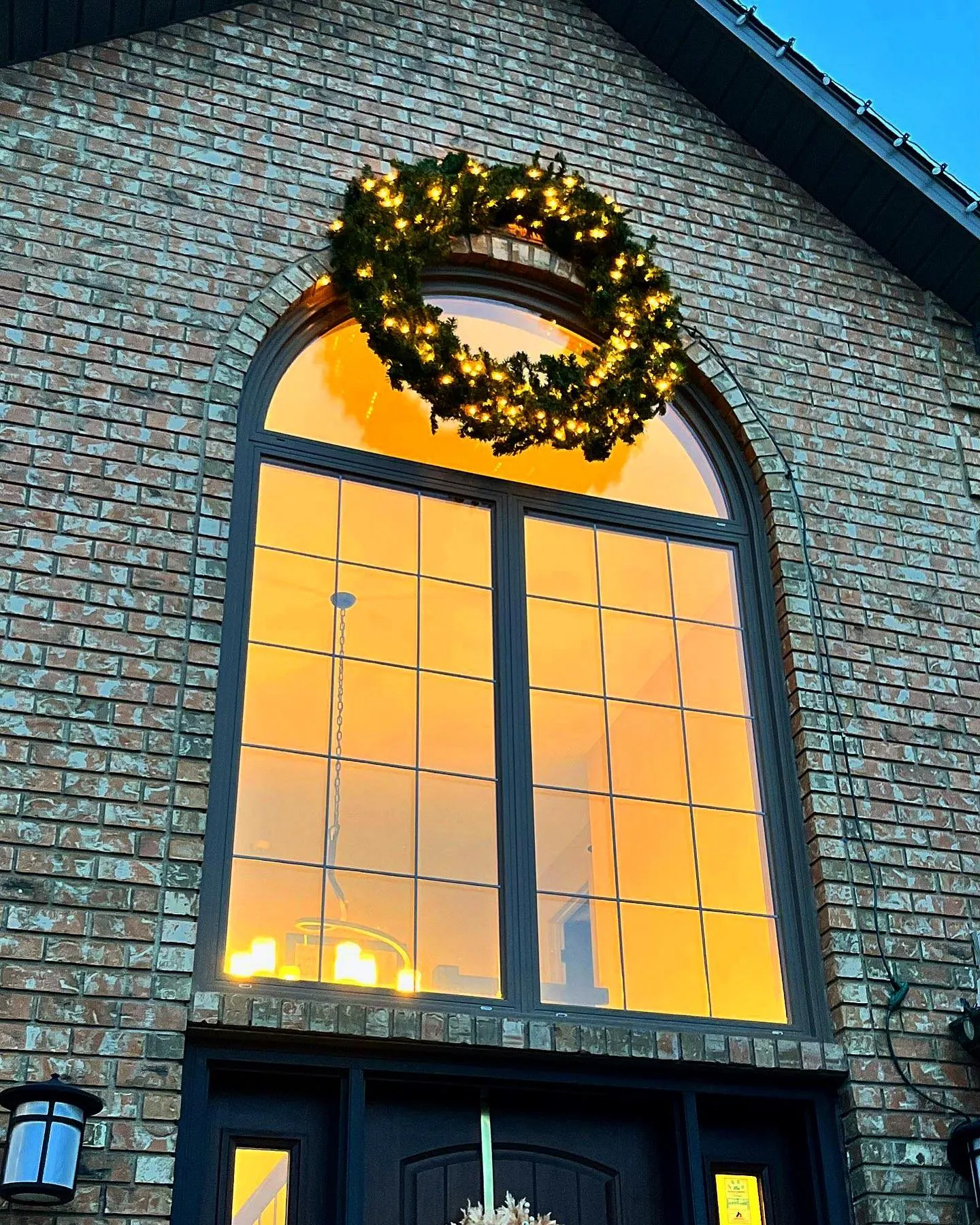 Lit wreath hung on the arched window of a brick Winnipeg home
