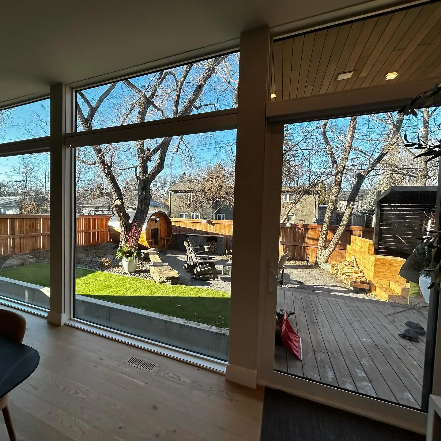 View through freshly cleaned floor-to-ceiling windows to a Winnipeg backyard deck