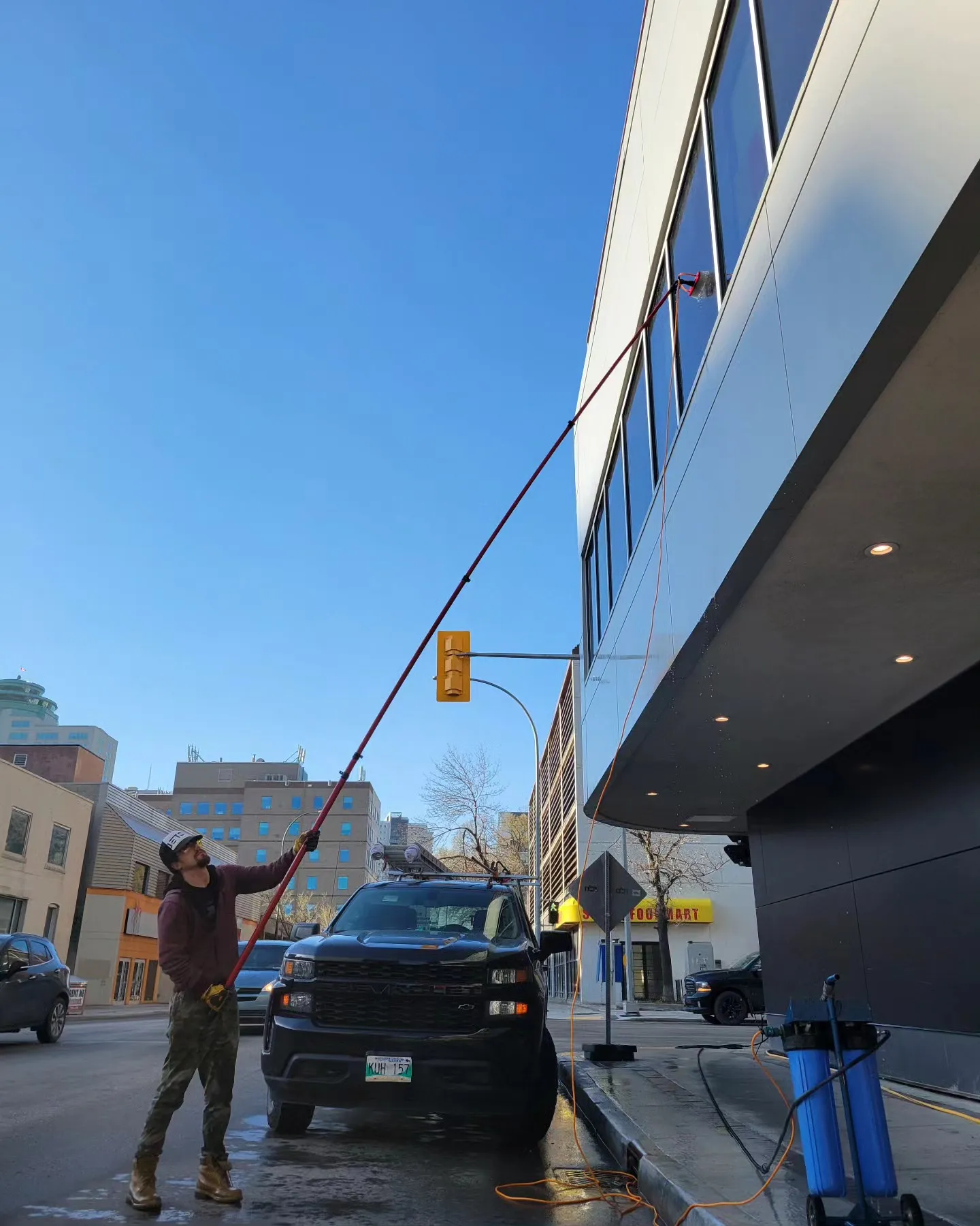Technician cleaning the windows of a Winnipeg office building with the Jet Set truck beside