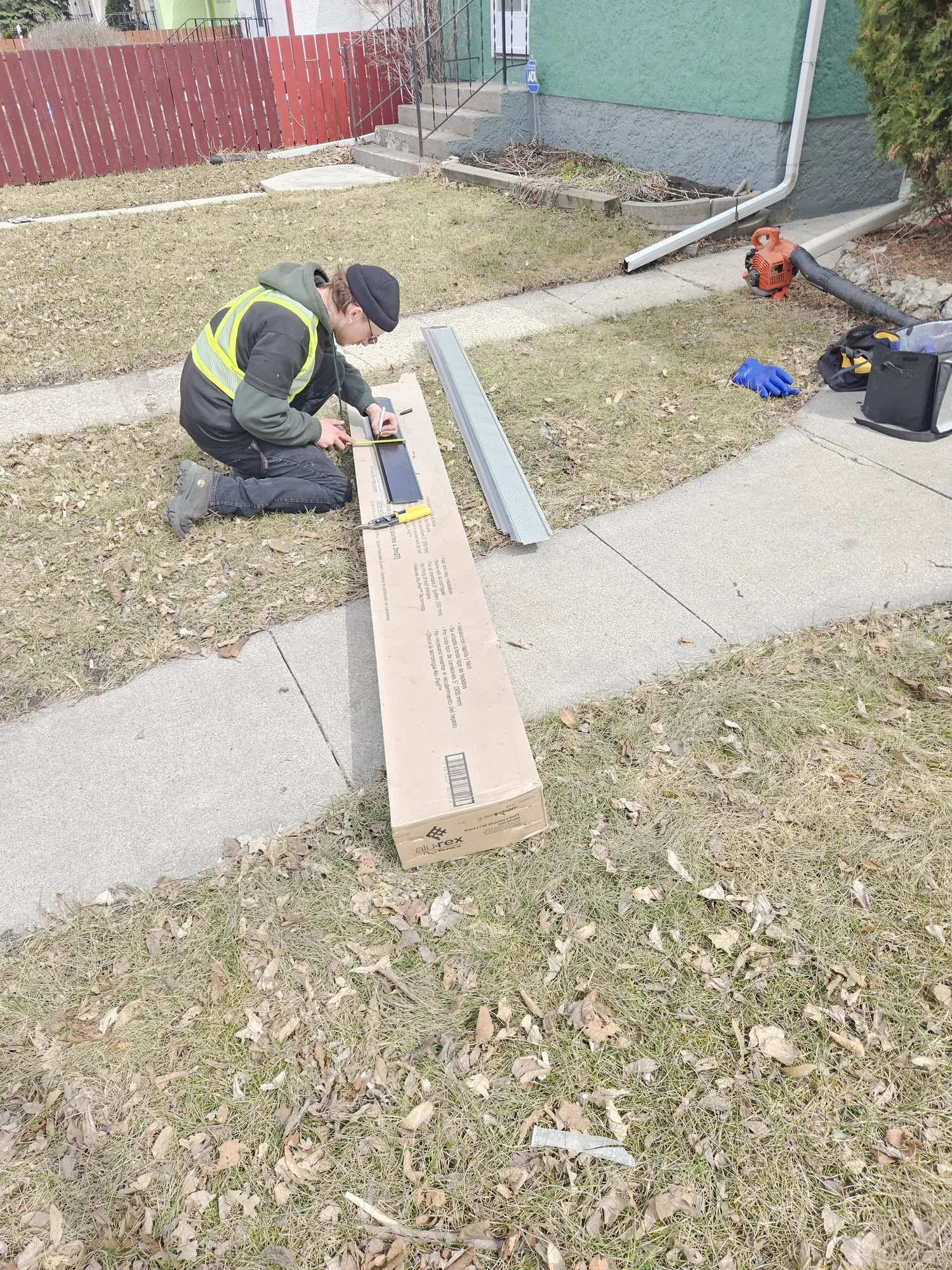 Jet Set technician on a Winnipeg lawn fitting a downspout extension beside the house