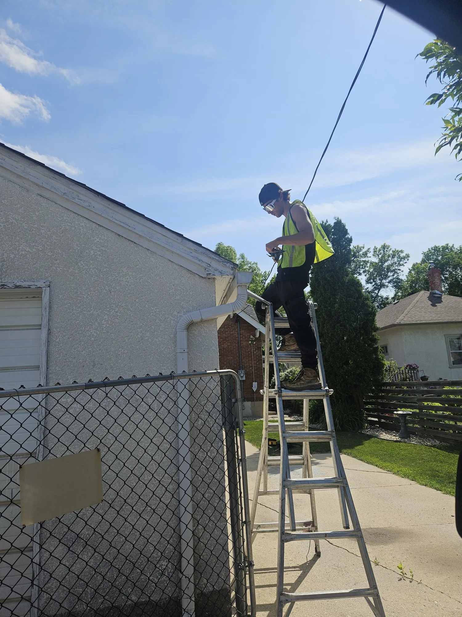 Jet Set technician on a ladder at the eaves of a Winnipeg bungalow on a sunny day
