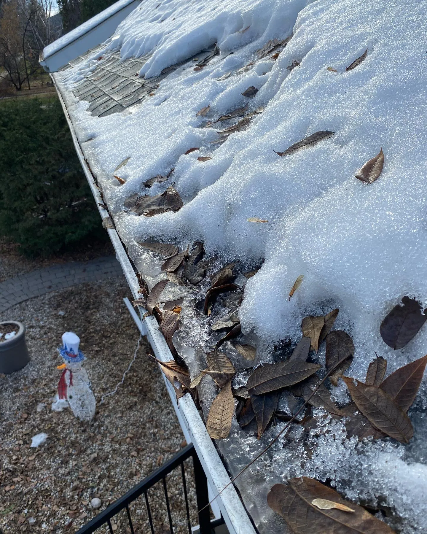 Eavestrough packed with leaves and early snow before a fall cleaning in Winnipeg
