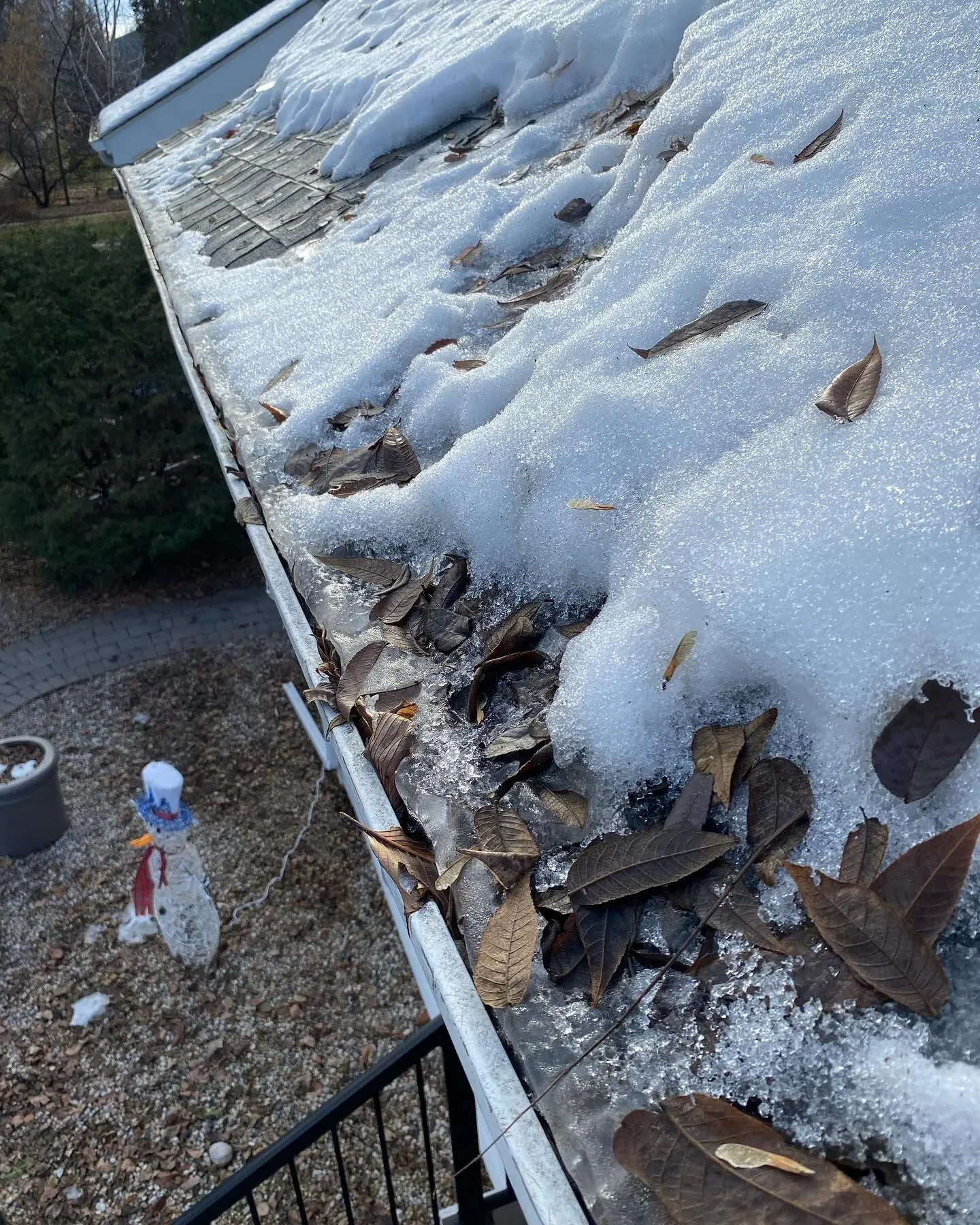 Eavestrough packed with leaves and snow before a fall cleaning