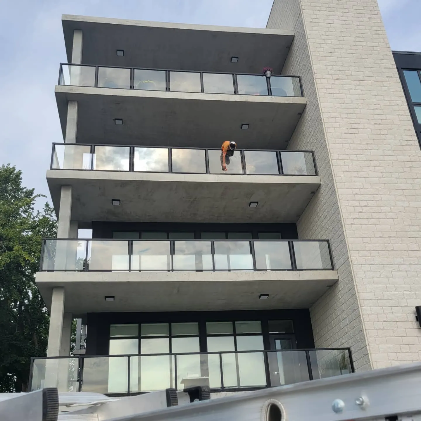 Technicians cleaning the glass balcony railings of a Winnipeg apartment building
