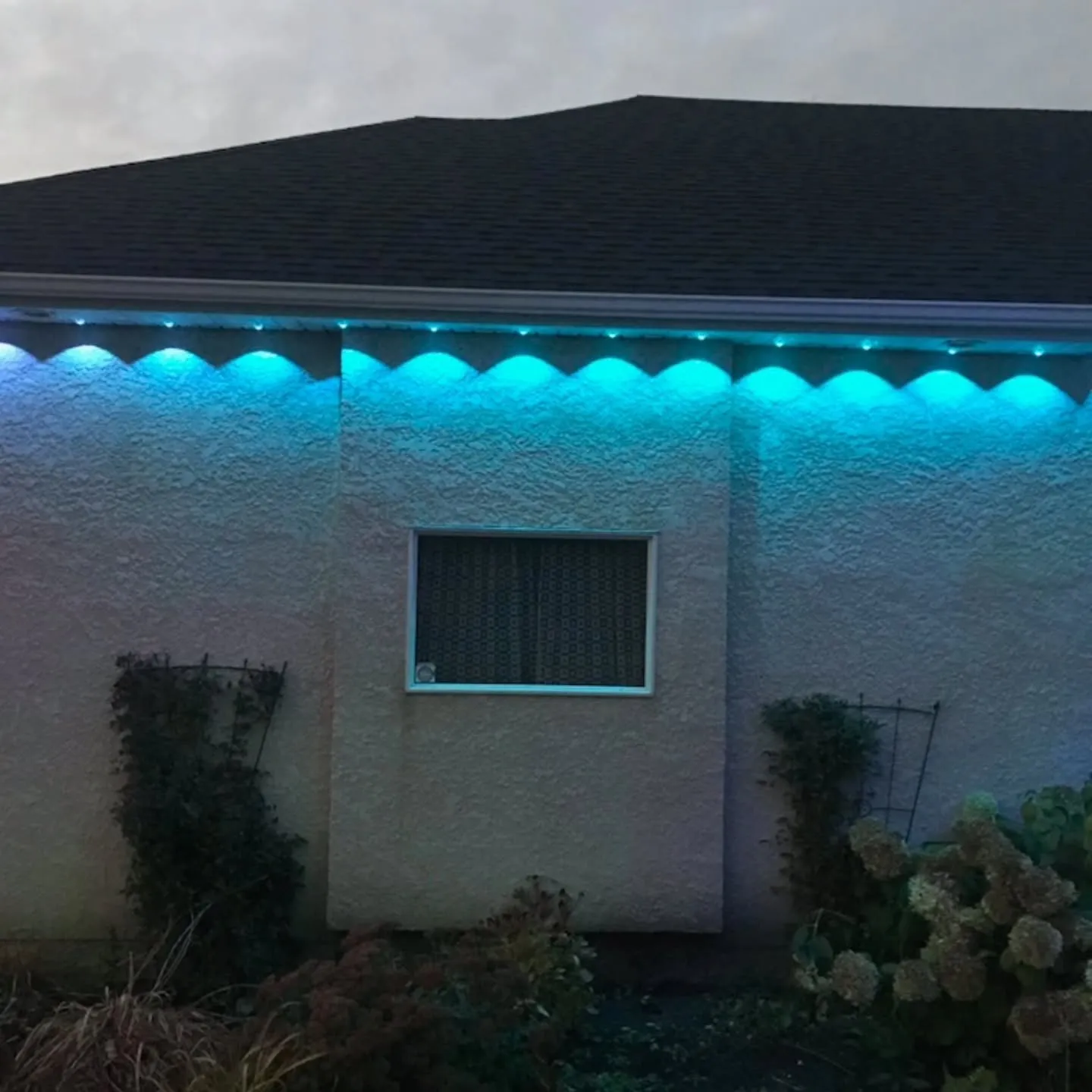 Cyan Govee permanent lights along the eave of a stucco home in Winnipeg