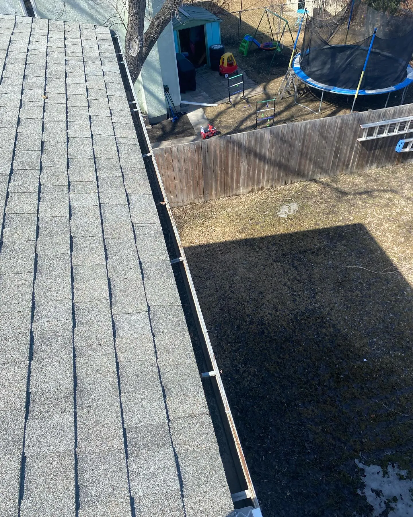 Gutter guard mesh installed along a shingle roof edge on a Winnipeg home