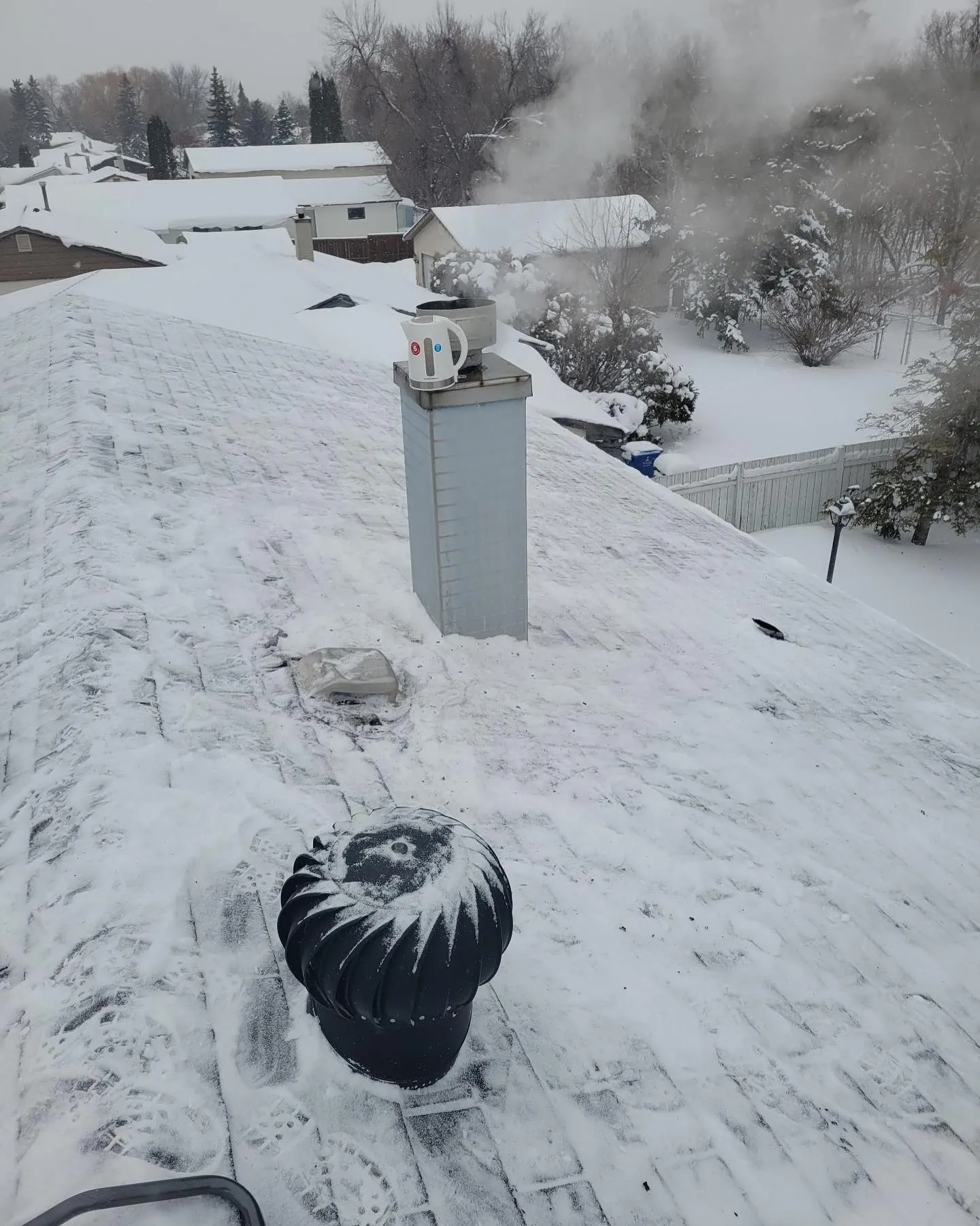 Snow-covered Winnipeg roof with a chimney and vent before clearing