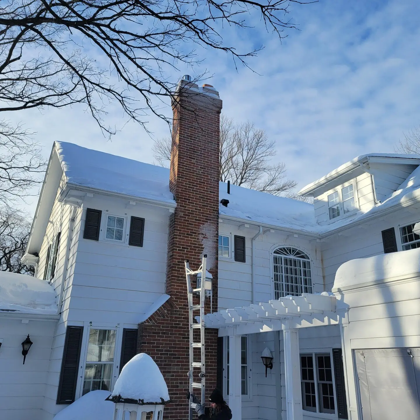 Ladder set against a snow-covered two-storey home for roof snow removal