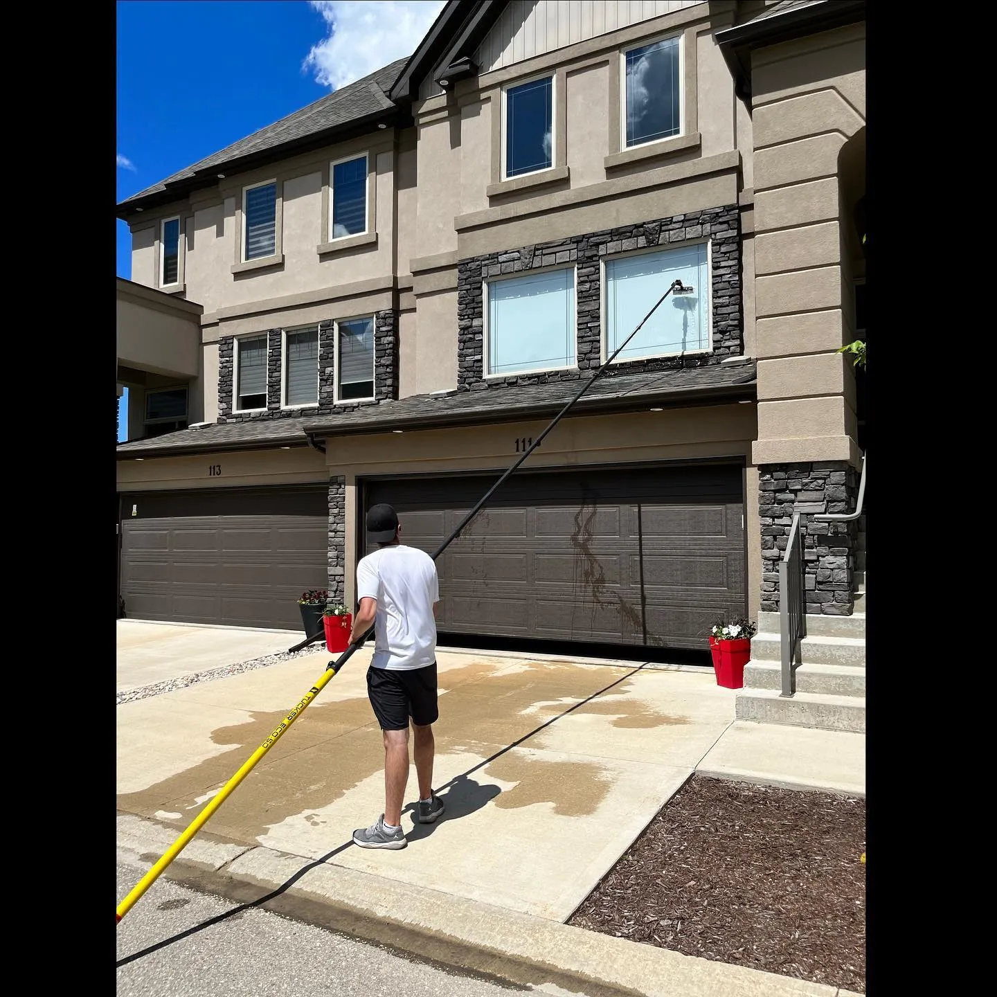 Upper windows of a Winnipeg townhouse being cleaned from the ground with a water-fed pole